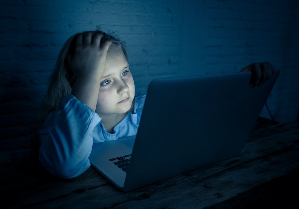 Scared sad girl bullied online on laptop suffering cyber bullying harassment. School girl humiliated on the internet by classmates feeling desperate and intimidated. Children victim of bullying.