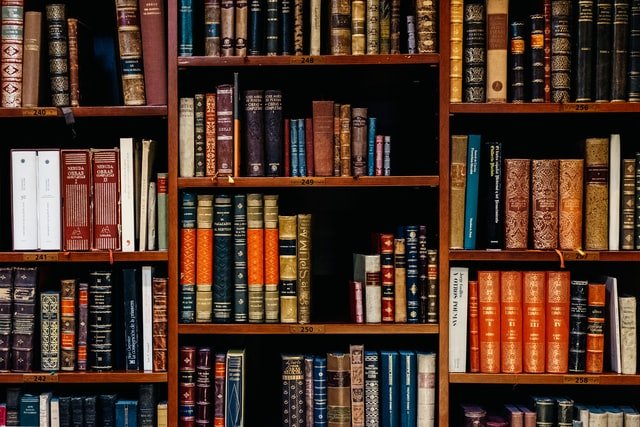 A bookcase full of old hard-back books of all colours