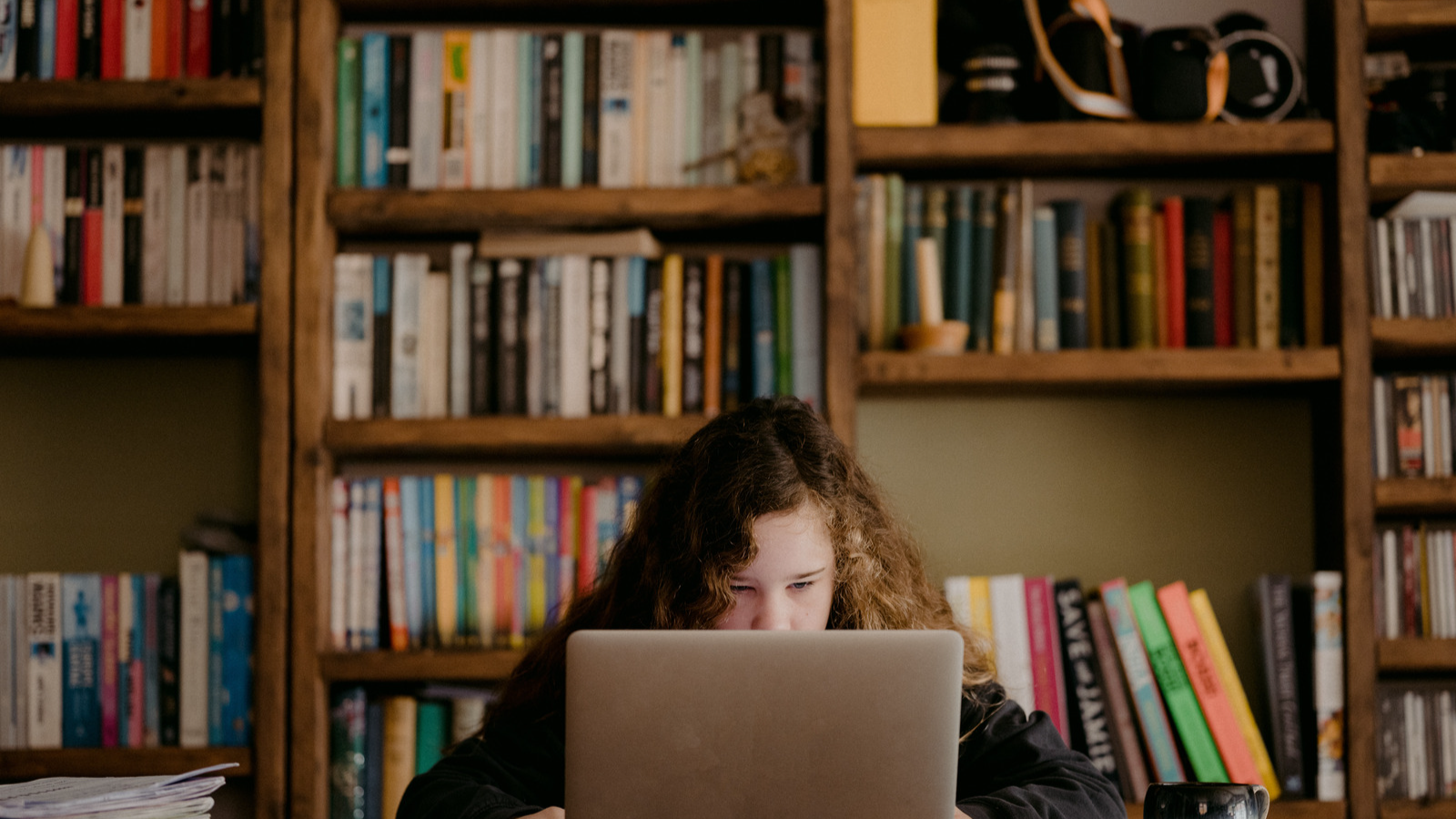 Young girl with red hair using a laptop in a library