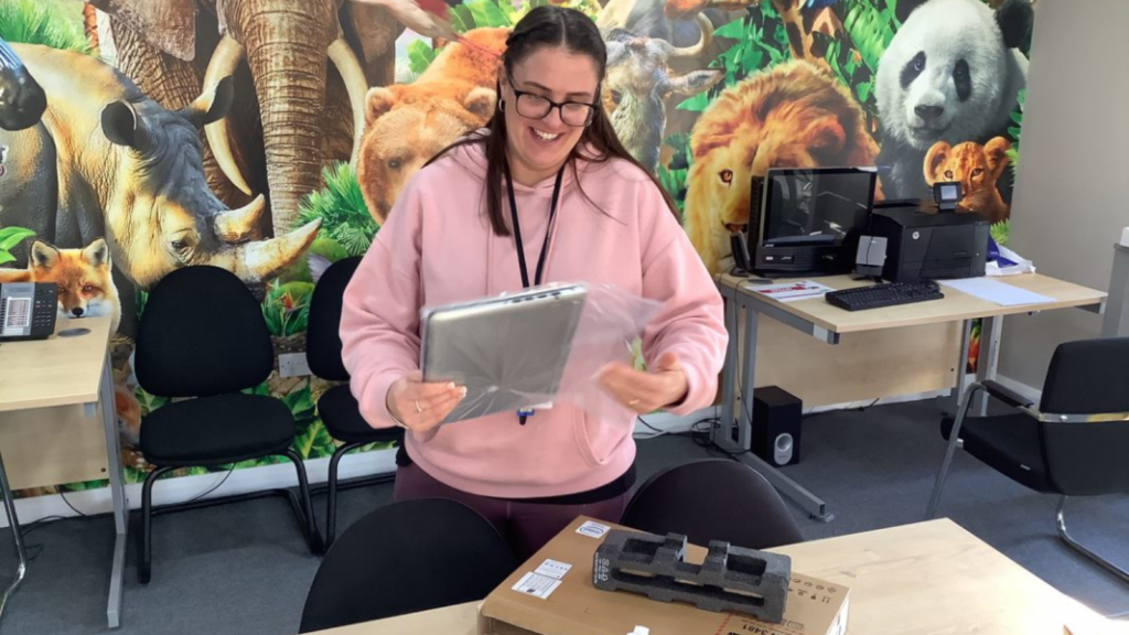 Young female teacher unwrapping their new laptop in the classroom.