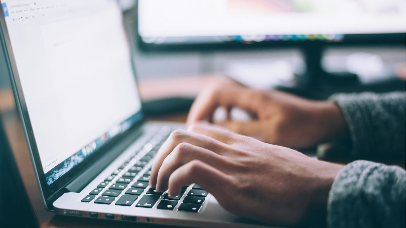 Man's hands typing on a laptop.