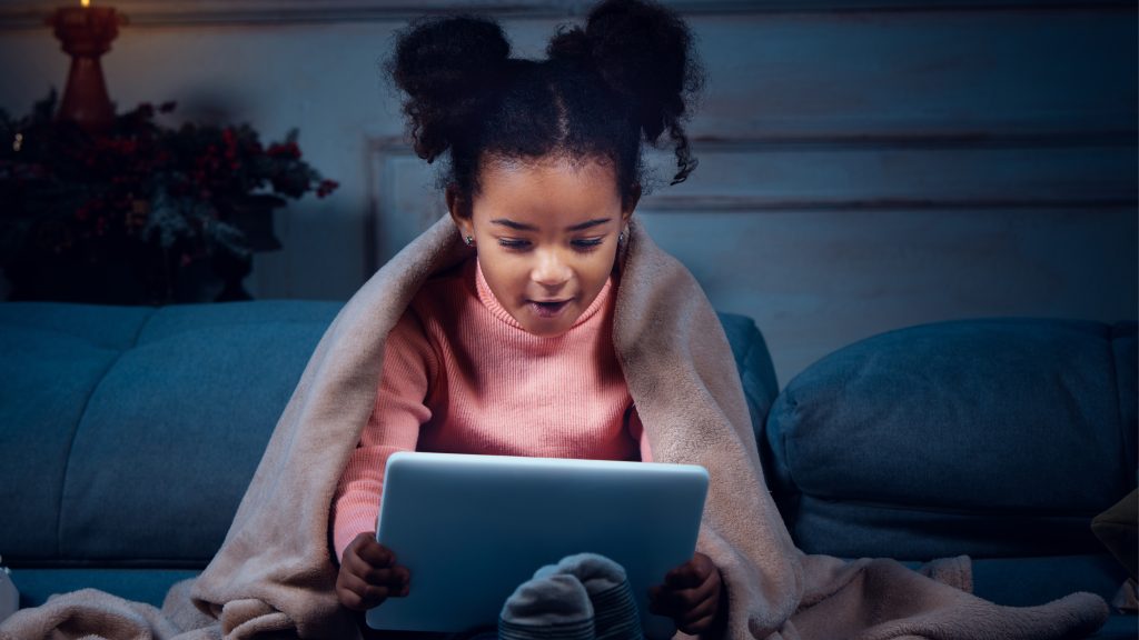 A young child sitting on the floor with her tablet.