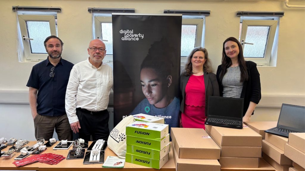 Members of Ealing Council and Digital Poverty Alliance standing behind a table with devices for community members.